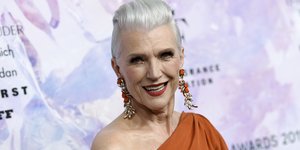 H Μάγια Μασκ με πορτοκαλί τοπ και μακριά σκουλαρίκια