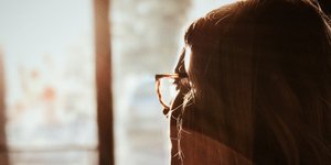 Μια γυναίκα φορά γυαλιά και κοιτάζει προς το παράθυρο