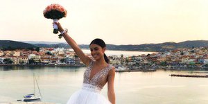 Η Μιρκέτα Βιδάλη νύφη στο γάμο της κρατά μια ανθοδέσμη με θέα τη θάλασσα