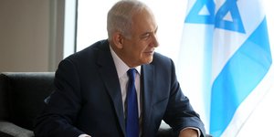 Ο Μπέντζαμιν Νετανιάχου κάθεται δίπλα σε σημαία του Ισραήλ