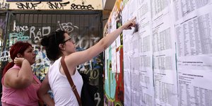 Μια υποψήφια κοιτάζει τη βαθμολογία της σε πίνακες που έχουν αναρτηθεί
