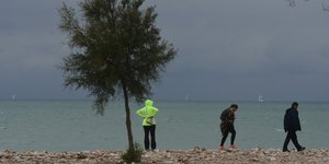 Βροχή σε θάλασσα με κόσμο και δέντρο