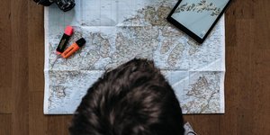 Ένας άνδρας πάνω από έναν χάρτη, ένα i-Pad, μια φωτογραφική μηχανή και μαρκαδόρους υπογράμμισης