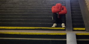 Αντρας με κόκκινη κουκούλα κάθεται στα σκαλιά