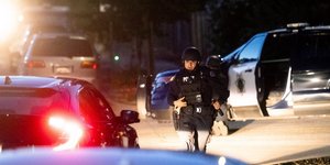 Αστυνομικός με όπλο ανάμεσα σε αυτοκίνητα