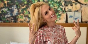 H Ντορέττα Παπαδημητρίου χαμογελάει και είναι καθισμένη σε ένα κρεβάτι