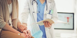 Γυναίκα με καφέ παντελόνι εξετάζεται από γιατρό