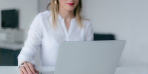 Γυναίκα με λευκά ρούχα εργάζεται μπροστά σε υπολογιστή
