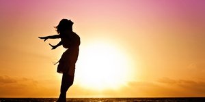 Σκιά γυναίκας που απολαμβάνει το ηλιοβασίλεμα στην παραλία