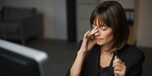 Γυναίκα με μαύρα ρούχα τρίβει τα μάτια της στο γραφείο