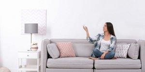 Γυναίκα ανοίγει το κλιματιστικό στο σπίτι της