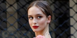 Μια γυναίκα με κόκκινο κραγιόν, μαύρο τοπ με ροζ λεπτομέρειες και μαύρο παντελόνι