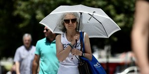 Γυναίκα με ομπρέλα θέλει να προστατευτεί από τον ζεστό καιρό και τον ήλιο