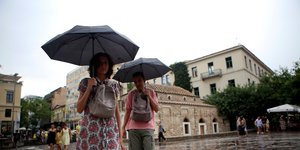 Γυναίκες κρατούν ομπρέλες στο Μοναστηράκι