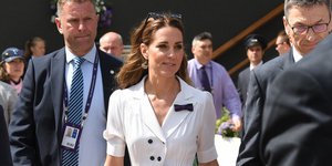 Η Κέιτ Μίντλετον με λευκό φόρεμα περπατάει χαμογελώντας