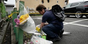 Κάτοικος αφήνει λουλούδια έξω από καμένο κτίριο