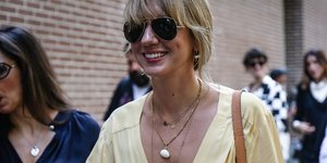 Γυναίκα με κίτρινο ρούχο χαμογελά στον δρόμο