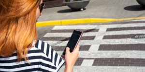 Γυναίκα διασχίζει δρόμο ενώ κοιτά το κινητό της