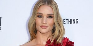 Η Ρόζι Χάντινγκτον με κόκκινη τουαλέτα χαμογελά στον φακό