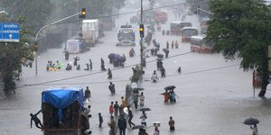 Άνθρωποι περπατούν μέσα στα νερά πλημμυρισμένης πόλης στην Ινδία