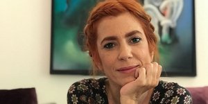 Η Μυρτώ Αλικάκη ακουμπάει το πηγούνι της και φοράει φόρεμα