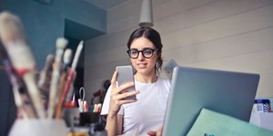 Γυναίκα σε γραφείο κοιτάζει το κινητό της