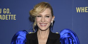 Η Κέιτ Μπλάνσετ με φουσκωτά σατέν μπλε μανίκια χαμογελάει 