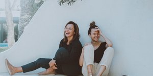 Δύο μελαχρινά κορίτσια χαμογελούν καθισμένες