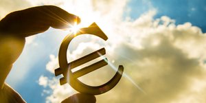 Το σήμα του ευρώ με φόντο τον ήλιο και τα σύννεφα