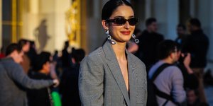 Γυναίκα στο δρόμο με σακάκι και γυαλιά ηλίου χαμοχελά