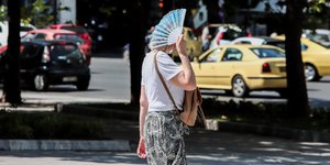Γυναίκα στο κέντρο της Αθήνας, προσπαθεί να προστατευθεί από τον καύσωνα