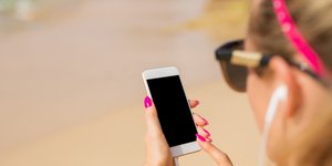 Γυναίκα με iphone κινητό στο χέρι στην παραλία