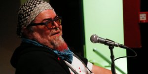 Ο Σταμάτης Κραουνάκης μπροστά σε ένα πιάνο και ένα μικρόφωνο