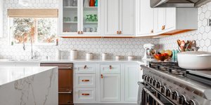 Mια κουζίνα με λευκά ντουλάπια, μαρμάρινο πάγκο και μαύρη ηλεκτρική κουζίνα