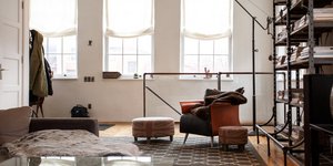 Σαλόνι διαμερίσματος με βιβλιοθήκη, πορτοκαλί πολυθρόνα, καφέ καναπέ, φωτιστικό