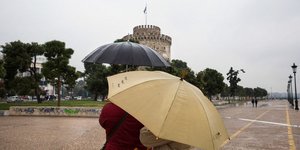 Βροχερός καιρός και κόσμος με ομπρέλες στο Λευκό Πύργο