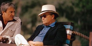 Ο Τρούμαν Καπότε καθισμένος σε καρέκλα με λευκό καπέλο και μαύρα γυαλιά