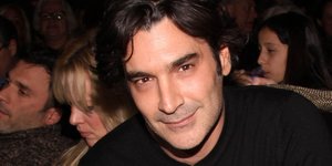 O Χριστόφορος Παπακαλιάτης χαμογελάει και φοράει τζιν και μαύρη μπλούζα