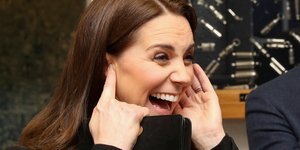 Η Κέιτ Μίντλετον με μαύρο παλτό γελά κρατώντας τα αυτιά της 