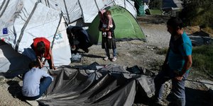 Μέλος ΜΚΟ βοηθά πρόσφυγες να στήσουν αντίσκηνο έξω από τον καταυλισμό της Μόρια