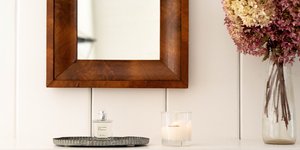 Καθρέφτης με ξύλινο πλαίσιο, αρωματικό κερί και λουλούδια σε βάζο