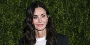 Η Κόρτνεϊ Κοξ με μπλε σακάκι και λευκό τοπ