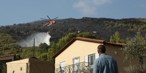 Κάτοικος κοιτάζει ελικόπτερο να ρίχνει νερό σε φωτιά