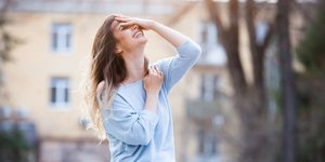 Μια γυναίκα με γαλάζια μπλούζα και λευκό παντελόνι χαμογελά