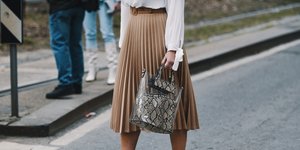 Γυναίκα με λευκό πουκάμισο, καφέ πλισέ φούστα, λευκά μποτάκια, λεοπάρ τσάντα