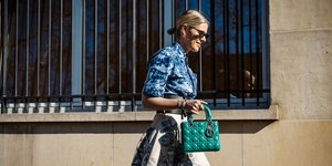 Ξανθά γυναίκα με μπλε πουκάμισο, μάξι φούστα και πράσινη τσάντα 