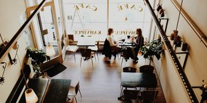 Δύο γυναίκες κάθονται σε ένα καφέ δίπλα σε τζαμαρία