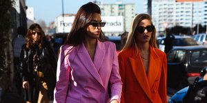 Δύο fashionista στο δρόμο με κοστούμια και γυαλιά 