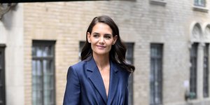 Η Κέιτι Χολμς περπατά στον δρόμο με μπλε κοστούμι