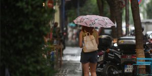 Κοπέλα κρατάει ομπρέλα στη βροχή